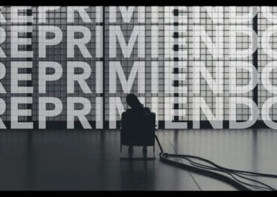 Una foto en blanco y negro de una persona sentada frente a una pared con palabras escritas en ella